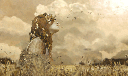 Gif em que uma menina ruiva está sentada em um campo e folhas secas voam em volta dela e em seu corpo.